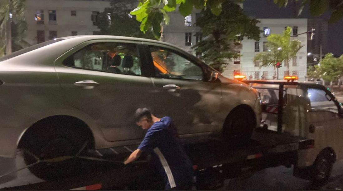 Equipe da PH Reboque amarrando carro na plataforma à noite